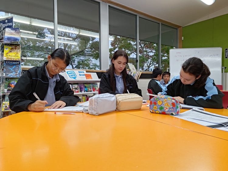 Three students working at an oragne coloured desk